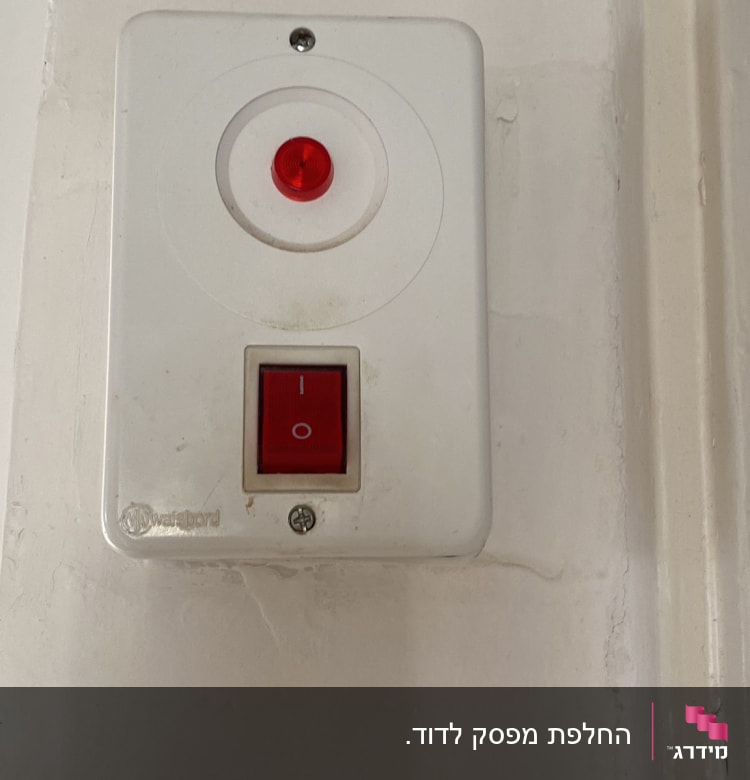 מתג חשמלי עם נורית חיווי אדומה על קיר